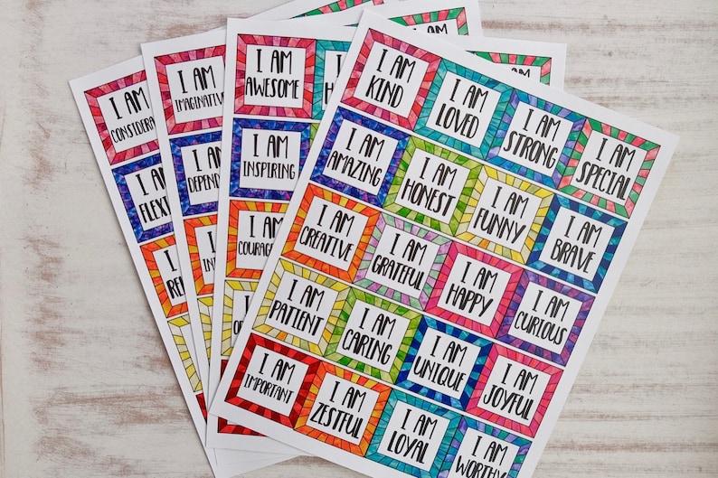 Op de afbeelding: Een set kleurrijke affirmatiecards met positieve boodschappen zoals "Ik ben geweldig", "Ik ben aardig" en "Ik ben creatief". De kaarten zijn gedrukt op wit papier en hebben een regenboogkleurige rand.