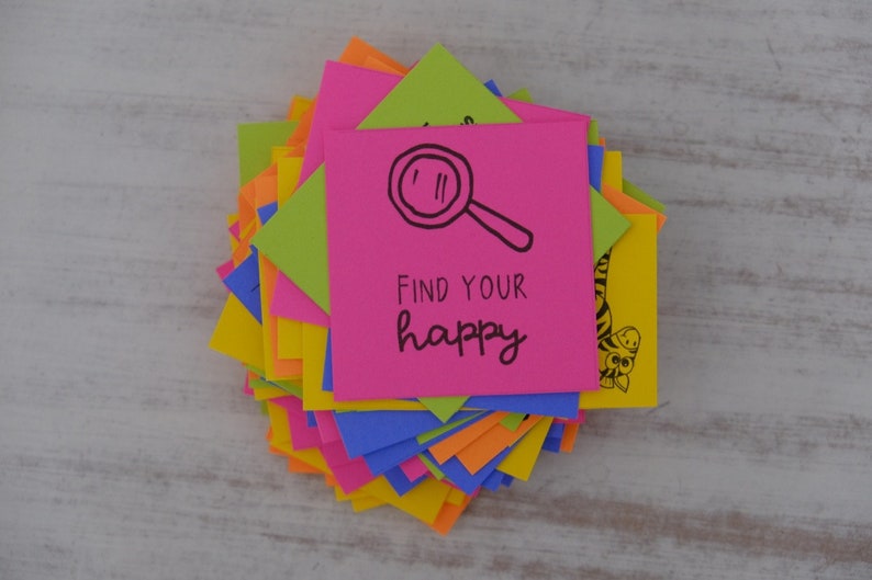 May include: A stack of colorful sticky notes with a pink note on top that says "Find your happy" with a magnifying glass drawn on it.