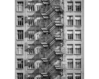 Könnte beinhalten: Ein Schwarzweißfoto eines hohen Gebäudes mit einer Feuertreppe. Die Feuertreppe ist aus Metall und hat viele Stufen. Das Gebäude hat viele Fenster.