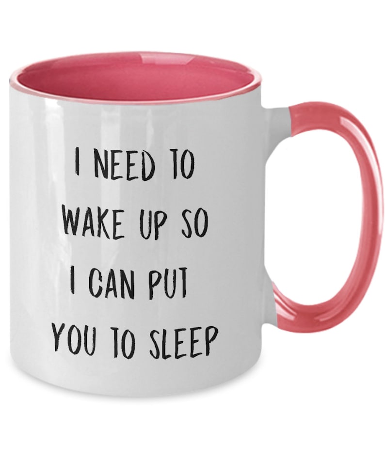 May include: White coffee mug with a pink rim and handle. The mug has black text that reads "I need to wake up so I can put you to sleep."