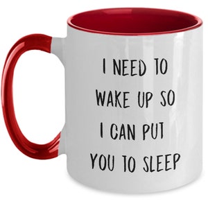 May include: White ceramic coffee mug with a red rim and handle. The mug has black text that reads "I need to wake up so I can put you to sleep."