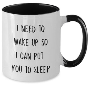 May include: White coffee mug with a black rim and handle. The mug has black text that reads "I need to wake up so I can put you to sleep."