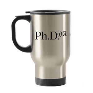 Peut inclure: Une tasse à café isotherme argentée avec une poignée et un couvercle noirs. La tasse porte l'inscription "Ph.D.iva" sur le côté.