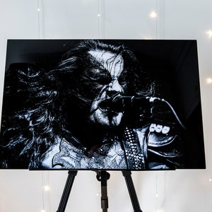 May include: Black and white photo of a musician singing into a microphone. The photo is printed on a canvas and displayed on an easel.