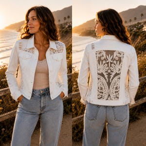 May include: A white denim jacket featuring intricate lace panels on the front shoulders and a large, detailed lace insert on the back. The jacket has a button-front closure, two chest pockets with flaps, and long sleeves, worn over a light top and jeans.