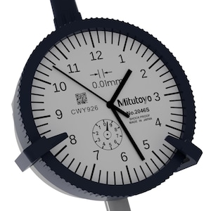 Puede incluir: Primer plano de un indicador de cuadrante Mitutoyo con esfera blanca, números negros y bisel azul oscuro. El dial muestra incrementos de 0,01 mm y el texto "Mitutoyo No.2046S SHOCK PROOF MADE IN JAPAN".