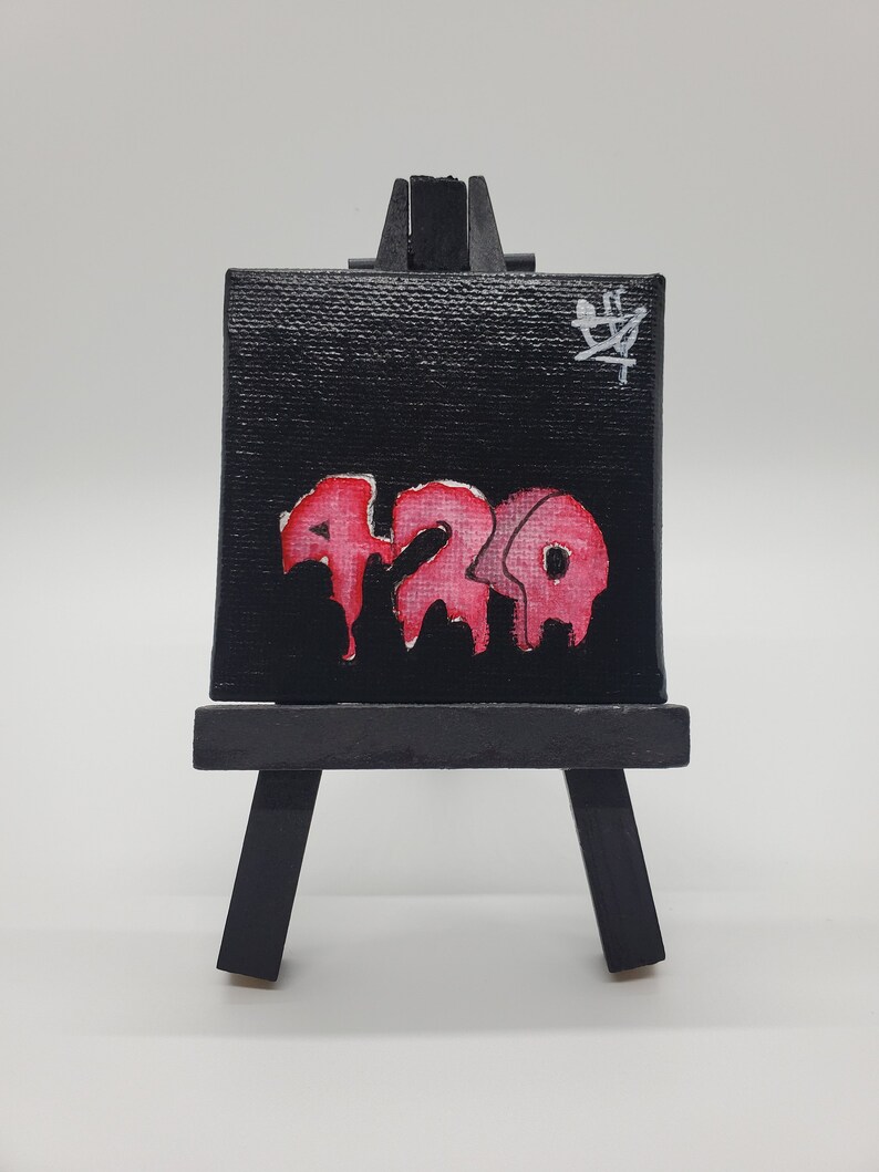 May include: A small black canvas painting on an easel with a red and pink dripping paint design that says "420" in a graffiti style. The canvas has a white inscription in the top right corner that says "草".