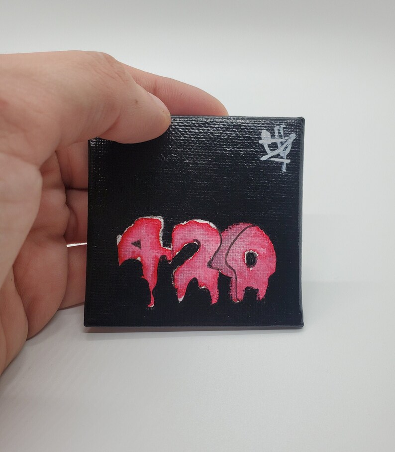 May include: A small black canvas painting with a pink dripping word "420" and a white signature in the top right corner.