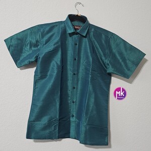 May include: A teal blue short-sleeved button-down shirt with a collar. The shirt has a subtle sheen and is made of a silky material.