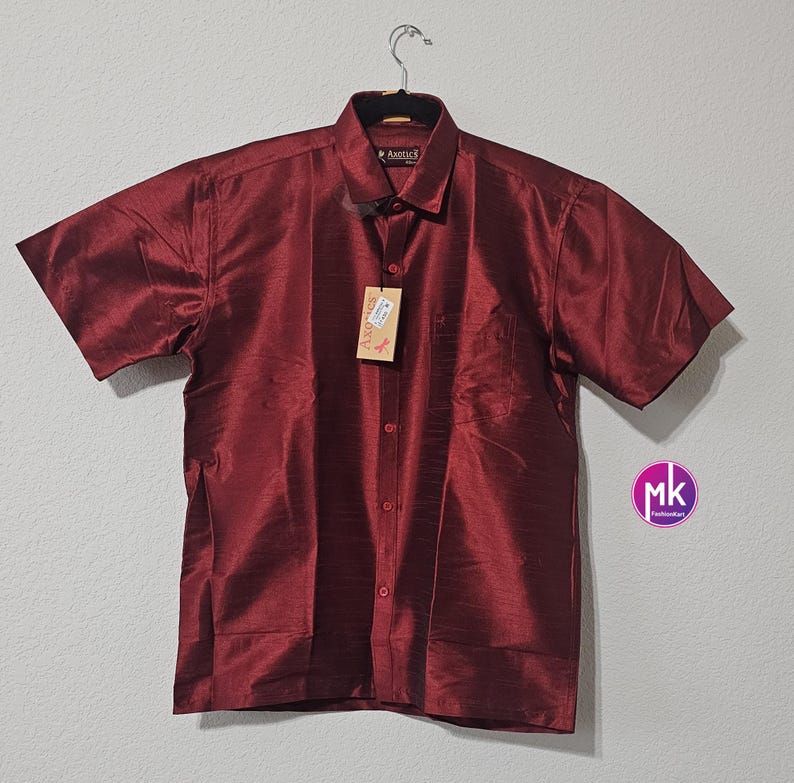 May include: A maroon short-sleeved button-down shirt with a pocket on the left side. The shirt is made of a silky material and has a subtle sheen.