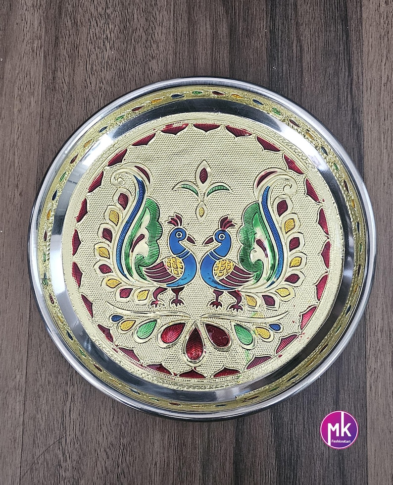 May include: A silver serving plate with a gold rim and a colorful peacock design. The plate features two peacocks facing each other with their tails spread out. The design is intricate and detailed, with a variety of colors including red, blue, green, and yellow.