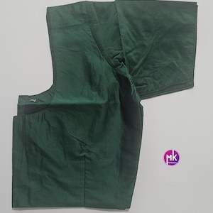 May include: A dark green blouse with short sleeves. The blouse has a simple, elegant design with a high neckline and a tailored fit. The fabric has a subtle sheen, giving it a luxurious appearance. The blouse is likely made of a lightweight material.