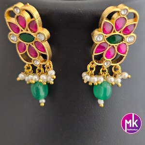 May include: A pair of gold earrings with pink and green stones, and white pearl accents. The earrings feature a floral design.