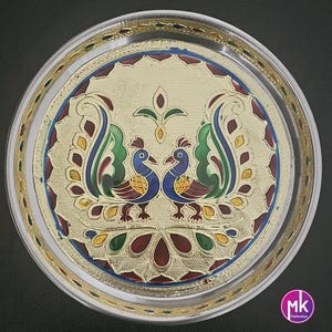 May include: A silver serving tray with a gold rim and a colorful peacock design. The tray features two peacocks facing each other with their tails spread out. The design is intricate and includes various colors, including green, blue, red, and gold.