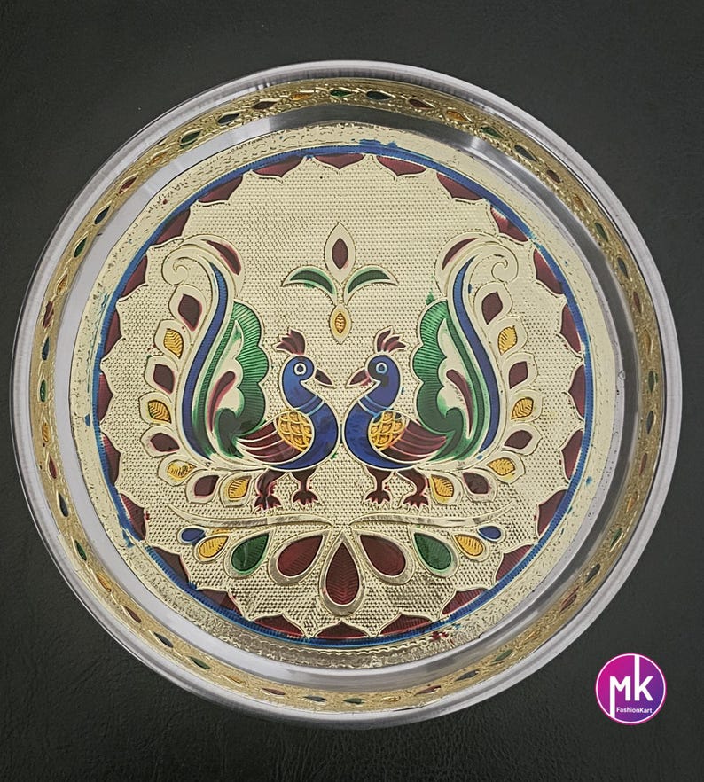 May include: A silver serving tray with a gold rim and a colorful peacock design. The tray features two peacocks facing each other with their tails spread out. The design is intricate and includes various colors, including green, blue, red, and gold.