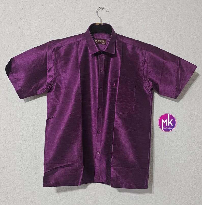 May include: A purple short-sleeved button-down shirt with a pocket on the left side. The shirt has a subtle sheen and a textured fabric.