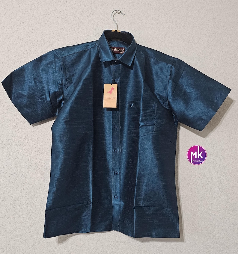 May include: A teal blue short-sleeved button-down shirt with a pocket on the left side. The shirt has a woven texture and is hanging on a hanger. The brand label says "Axxia".