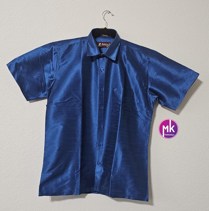 May include: A blue short-sleeved button-down shirt with a subtle sheen. The shirt has a collar and a button closure. The brand name "Angelic" is visible on the collar.