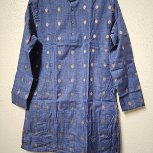 May include: A blue long-sleeved shirt with a mandarin collar and gold polka dots. The shirt has a button closure at the neck.