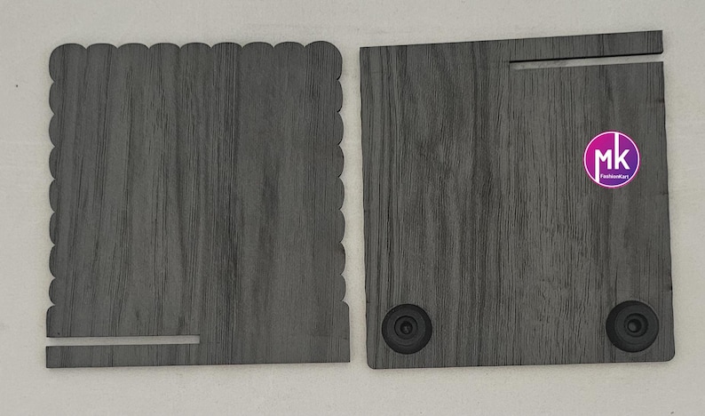 May include: Two dark gray wood-grain panels. The left panel has a scalloped top edge and a horizontal slot at the bottom. The right panel features a horizontal slot at the top, two black circular feet at the bottom, and a circular pink logo with mk.