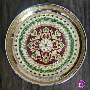 May include: A silver serving platter with a decorative design featuring a red, white, and green floral pattern. The platter has a gold rim and is perfect for serving food or displaying decorative items.