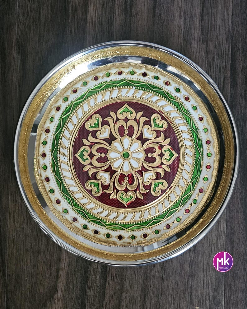May include: A silver serving platter with a decorative design featuring a red, white, and green floral pattern. The platter has a gold rim and is perfect for serving food or displaying decorative items.