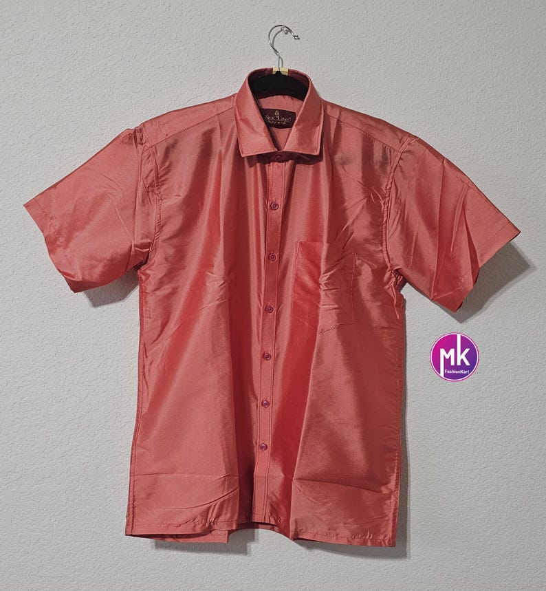 May include: A coral colored short-sleeved button-down shirt with a pocket on the left side. The shirt is made of a silky material and has a collar.