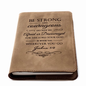 Könnte beinhalten: Ein braunes, ledergebundenes Tagebuch mit der Inschrift "BE STRONG AND courageous DO NOT BE Afraid or Discouraged FOR THE LORD YOUR GOD IS WITH YOU WHEREVER YOU GO Joshua 1:9"