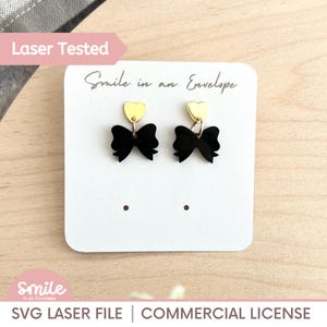 May include: Black bow earrings with gold heart accents, displayed on a white card. The card has the text "Smile in an Envelope" and "Laser Tested". The bottom of the card reads "SVG LASER FILE | COMMERCIAL LICENSE".