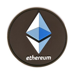 May include: A round, black patch featuring the Ethereum logo, a stylized diamond shape in shades of blue and white. The word "ethereum" is printed in white at the bottom of the patch.