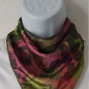 May include: A green, pink, and black patterned silk scarf with a green stitched edge.