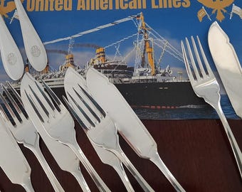 Könnte beinhalten: Ein Set aus silberfarbenem Besteck, bestehend aus Gabeln und Messern mit glatten, polierten Griffen. Das Besteck ist auf einer rechteckigen Werbekarte angeordnet, die einen Ozeandampfer und den Text United American Lines zeigt.