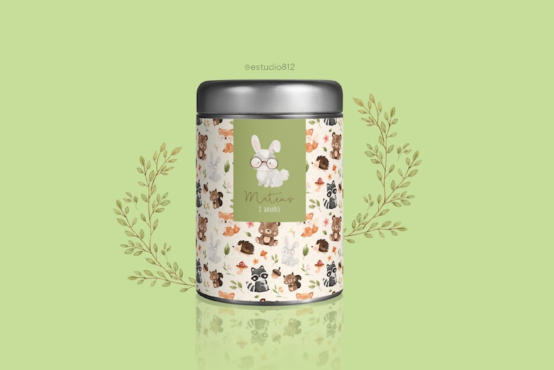 May include: A silver metal container with a green label featuring a cartoon bunny wearing glasses. The label says "Mateus 1 ano". The container is decorated with a pattern of woodland animals, including foxes, bears, raccoons, and squirrels.