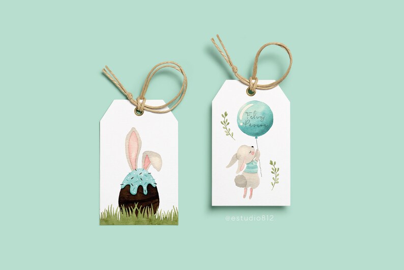 May include: Two white gift tags with watercolor illustrations. One features a bunny with an Easter egg, the other a bunny holding a balloon with the text "Feliz P&aacute;scoa". Both tags have twine for hanging.