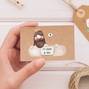 May include: A brown card with a cartoon illustration of Jesus holding a bandage with the text "It's gonna be okay".