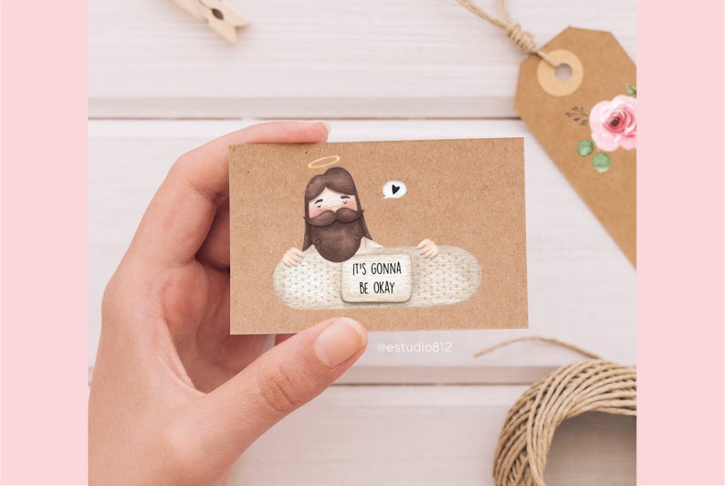 May include: A brown card with a cartoon illustration of Jesus holding a bandage with the text "It's gonna be okay".
