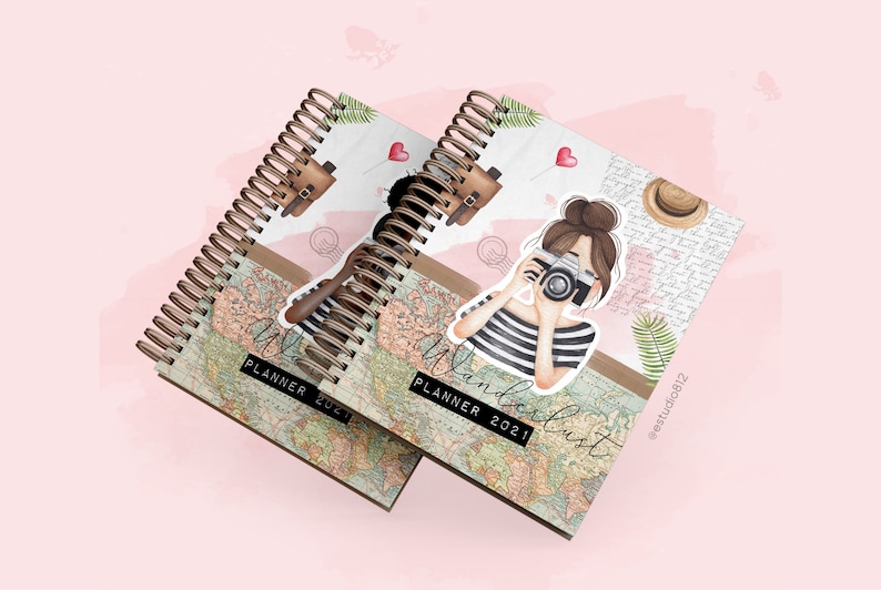 Op de afbeelding: Twee bruine spiraalgebonden planners met een vintage wereldkaartontwerp. De voorkant heeft een cartoonillustratie van een vrouw met bruin haar die een foto maakt met een camera. De tekst op de omslag luidt "Wanderlust Planner 2021".