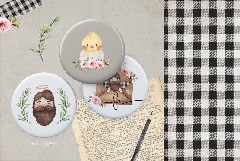 May include: Three round buttons with religious imagery. The first button has a gray background with a yellow chick and pink flowers. The second button has a white background with a brown-haired man with a halo and a green leafy border. The third button has a white background with a brown-haired man in a brown envelope with the word "fe" written on it.