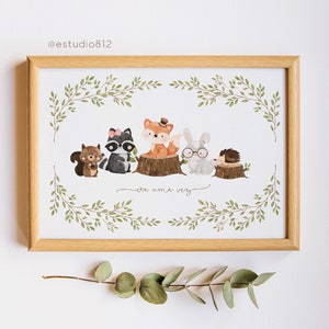 May include: A framed print with a watercolor illustration of five woodland animals, including a raccoon, fox, rabbit, squirrel, and hedgehog. The animals are standing on tree stumps and surrounded by green leaves. The text "era una vez" is written below the animals.