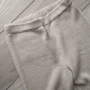 May include: A pair of beige knitted leggings with a ribbed texture.