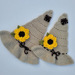 May include: Two crocheted witch hats with sunflower embellishments. The hats are beige with brown stitching and yellow and brown sunflowers.