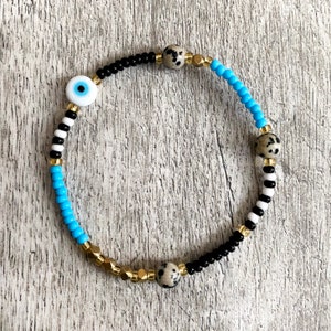 Black, turquoise and gold beaded bracelet with evil eye and Dalmatian Jasper beads. Handmade.