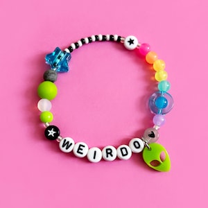 May include: A colourful beaded bracelet with a green alien charm and the word "WEIRDO" spelled out in white beads.