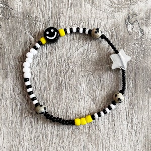 Beaded smiley fidget bracelet. Dalmatian Jasper beads, acrylic smiley, glow in the dark star and glass beads in black, white and yellow.