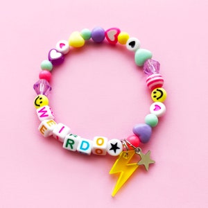 Pastellfarbenes Regenbogen-Perlenarmband. Kann mit jedem Namen oder Wort personalisiert werden. Charm aus Metall mit Blitz und Stern. Smileys und Herzen.