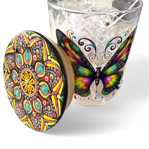 May include: A glass candle jar with a colourful butterfly design on the front. The lid is decorated with a black, yellow, pink and turquoise mandala design.