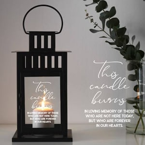 Puede incluir: Linterna de metal negro con un panel de vidrio que presenta el texto "Esta vela arde en memoria de aquellos que no están aquí hoy, pero que están para siempre en nuestros corazones."