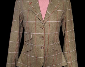 May include: A green, brown, and white plaid blazer with red trim and four buttons. The blazer is on a mannequin with a pink turtleneck.