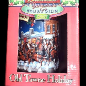 Può includere: Una scatola rossa con un Budweiser Christmas Holiday Stein. Lo stein raffigura una scena invernale con cavalli e un edificio. La scatola riporta le scritte "Holiday Stein 2000" e "Old Town Holiday".