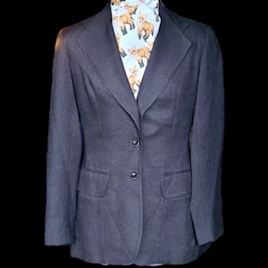 Peut inclure: Un blazer gris foncé avec une fermeture à trois boutons et deux poches à rabat. Le blazer est porté sur une chemise blanche à imprimé renard.